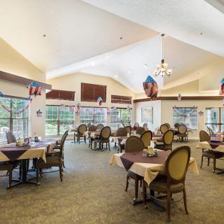 A spacious dining room with neatly arranged tables and chairs, featuring large windows and elegant decor.