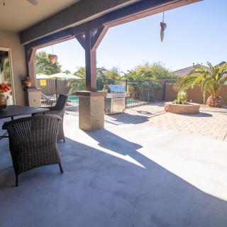 A spacious outdoor patio with furniture overlooking a sunny backyard and pool.