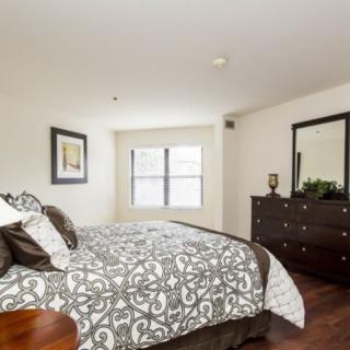 A well-decorated bedroom with a patterned bedspread and a dresser next to a window.