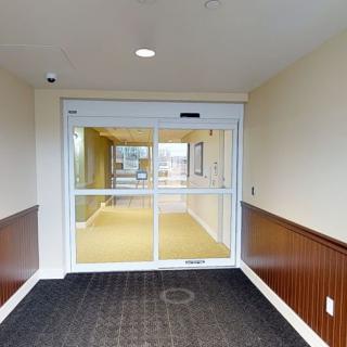 A well-lit entrance hallway with an automatic sliding door and carpeted flooring.