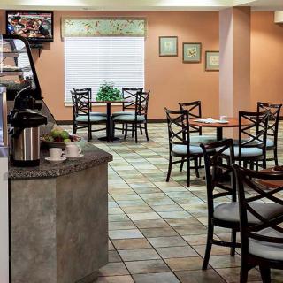 A cozy indoor cafe with empty tables and chairs, featuring warm decor and tiled flooring.