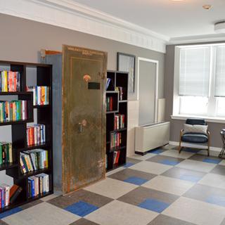 A cozy office space featuring bookshelves filled with books, a large safe, and comfortable seating.
