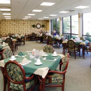 A spacious and elegantly furnished dining room with tables set for a meal, featuring large windows allowing natural light to illuminate the space.