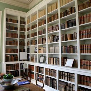 A cozy home library with tall white bookshelves filled with books.