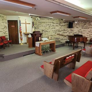 A peaceful interior view of a church sanctuary featuring wooden pews and a pulpit.