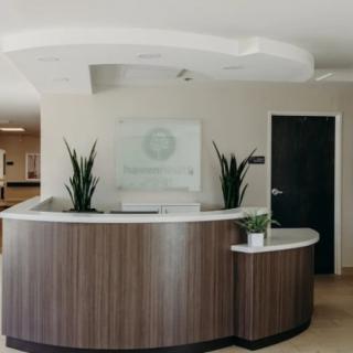 A modern reception desk with plants and a welcoming interior.