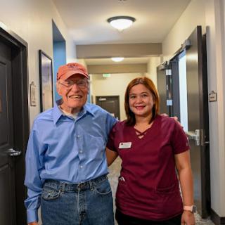 A joyful moment between an elderly man and a nurse in a healthcare facility.
