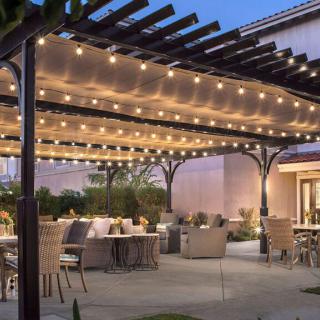A cozy outdoor patio with a pergola adorned with string lights, featuring comfortable seating and a welcoming atmosphere.