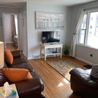 A cozy living room with a sofa, TV, and large window letting in natural light.