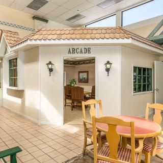 Indoor arcade area with seating and decorative house-like structure.