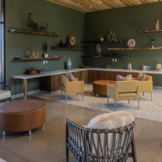 A modern living room with stylish furniture and minimalist decor, featuring a green accent wall and wooden ceiling.