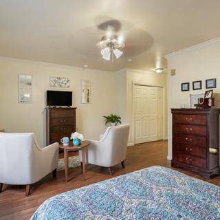 A cozy bedroom featuring comfortable chairs, a television, and elegant wooden furniture.