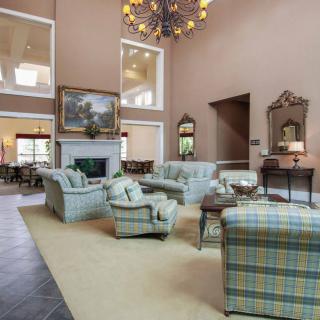 A spacious, elegantly decorated living room with plush seating, a fireplace, and a large chandelier.