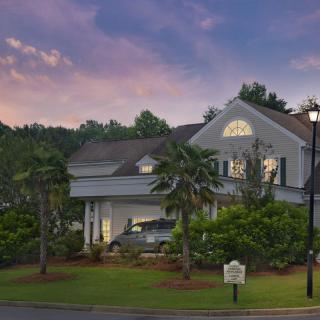 A suburban house with well-maintained landscaping set against a sunset sky.