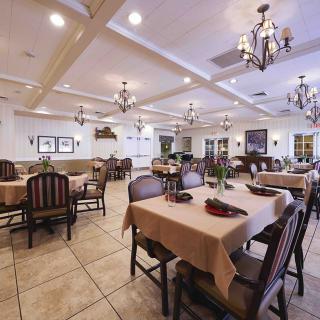 A spacious dining area with neatly arranged tables and elegant chandeliers.