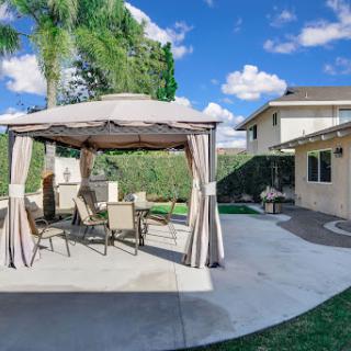 A cozy outdoor gazebo with seating in a well-maintained backyard.