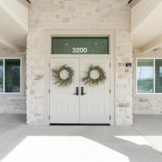 A building entrance with double doors adorned with wreaths and the number 2020.
