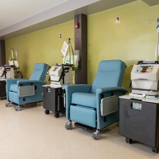 An infusion room with medical chairs and equipment lined up against a wall.