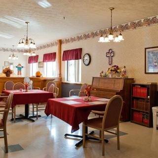 A cozy dining area with tables and chairs, featuring a piano and traditional decorations.