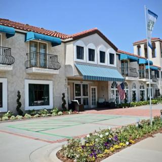 A charming hotel exterior with decorative awnings, flags, and vibrant flowerbeds.