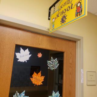 A decorated classroom door featuring autumn-themed leaf cutouts and a welcoming sign.