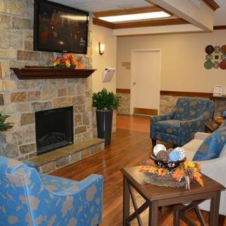 A cozy living room with a stone fireplace, television, and comfortable seating.