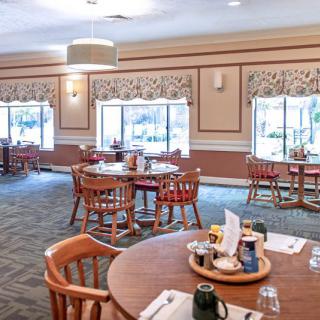 A well-lit dining area with neatly arranged tables and chairs.