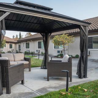 A cozy outdoor gazebo with comfortable seating in a backyard setting.