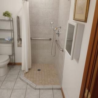 A bathroom with a walk-in shower, grab bar, and tiled floor.