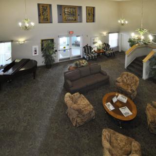 A spacious lobby area featuring comfortable seating, a piano, and elegant chandeliers.