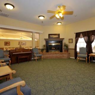 A cozy living room featuring comfortable chairs, a fireplace, and a ceiling fan.