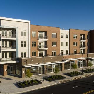 A modern residential apartment building with retail storefronts on the ground floor.