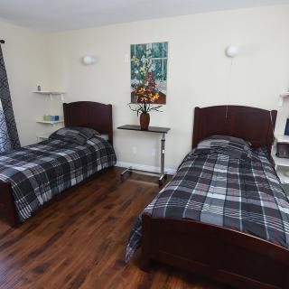 A modern bedroom with twin beds and wooden flooring.