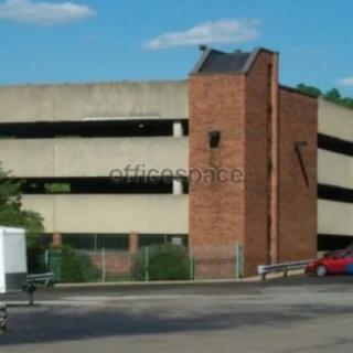 A multi-level parking garage with a brick stairwell on a clear day.
