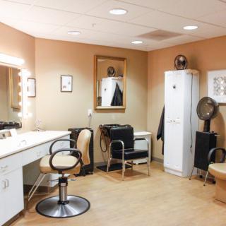 A well-equipped dressing room featuring a lighted vanity mirror and hairstyling station.