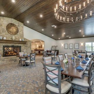A spacious dining room with a rustic design, featuring a large fireplace and elegant chandelier.