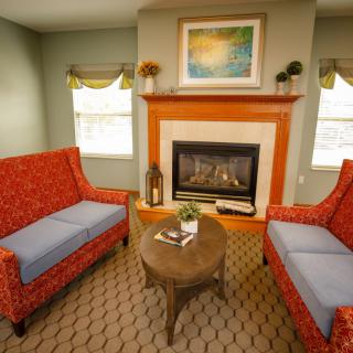 A cozy living room featuring a fireplace, two red couches, and a central wooden coffee table.