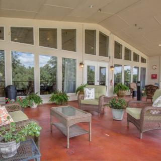 A spacious patio with comfortable wicker furniture and lush greenery offers a relaxing outdoor seating area.