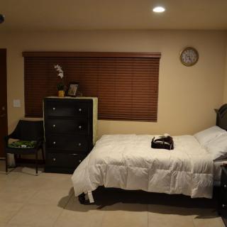 A neatly organized bedroom with a bed, dresser, and window blinds.