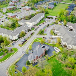 Aerial view of a suburban residential area with buildings surrounded by greenery and intersecting roads.