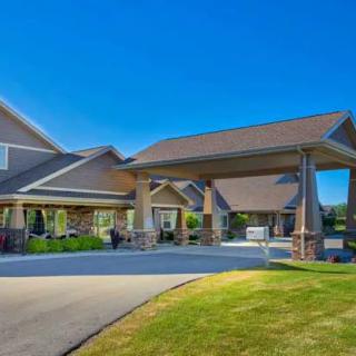 A modern residential building with a driveway and well-maintained landscaping under a clear blue sky.