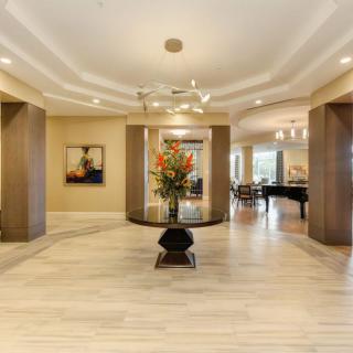A luxurious foyer with elegant decor, featuring a central floral arrangement and a grand piano in the background.