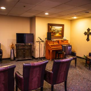 A cozy room with chairs, a television, and a piano under warm lighting.