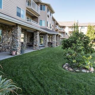 A well-maintained lawn in front of an apartment building with stone columns and balconies.