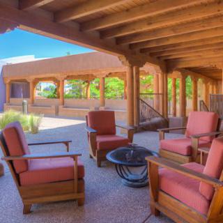 A cozy outdoor patio with wooden chairs and a fire pit under a covered terrace.