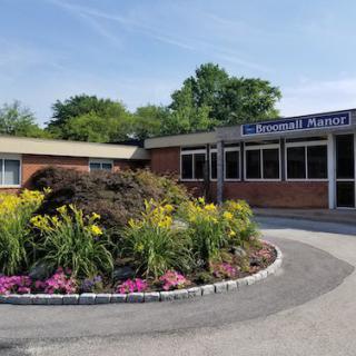 The entrance of a school building with well-maintained landscaping and colorful flowers.