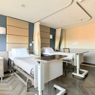 A modern hospital patient room featuring two adjustable beds and a serene environment.
