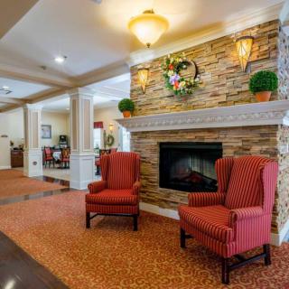 A cozy living room with a stone fireplace and two red armchairs.