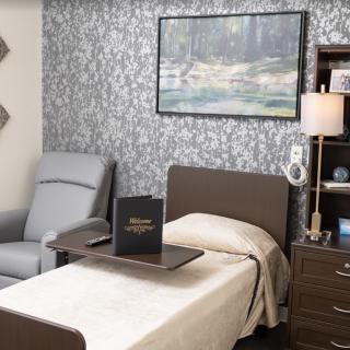 A cozy bedroom with a single bed, side table, armchair, and decorative wall art.