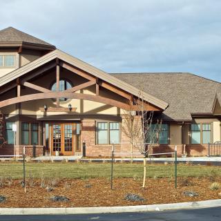 A large building with a gabled roof and extensive landscaping in front.